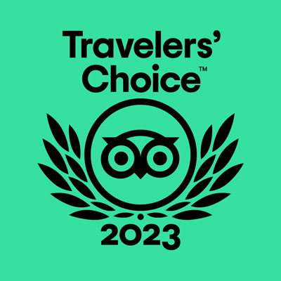 Black “Travelers’ Choice 2023” text and owl logo with laurel leaves on a green background, representing an award from Tripadvisor for outstanding lodging in Kanab UT.